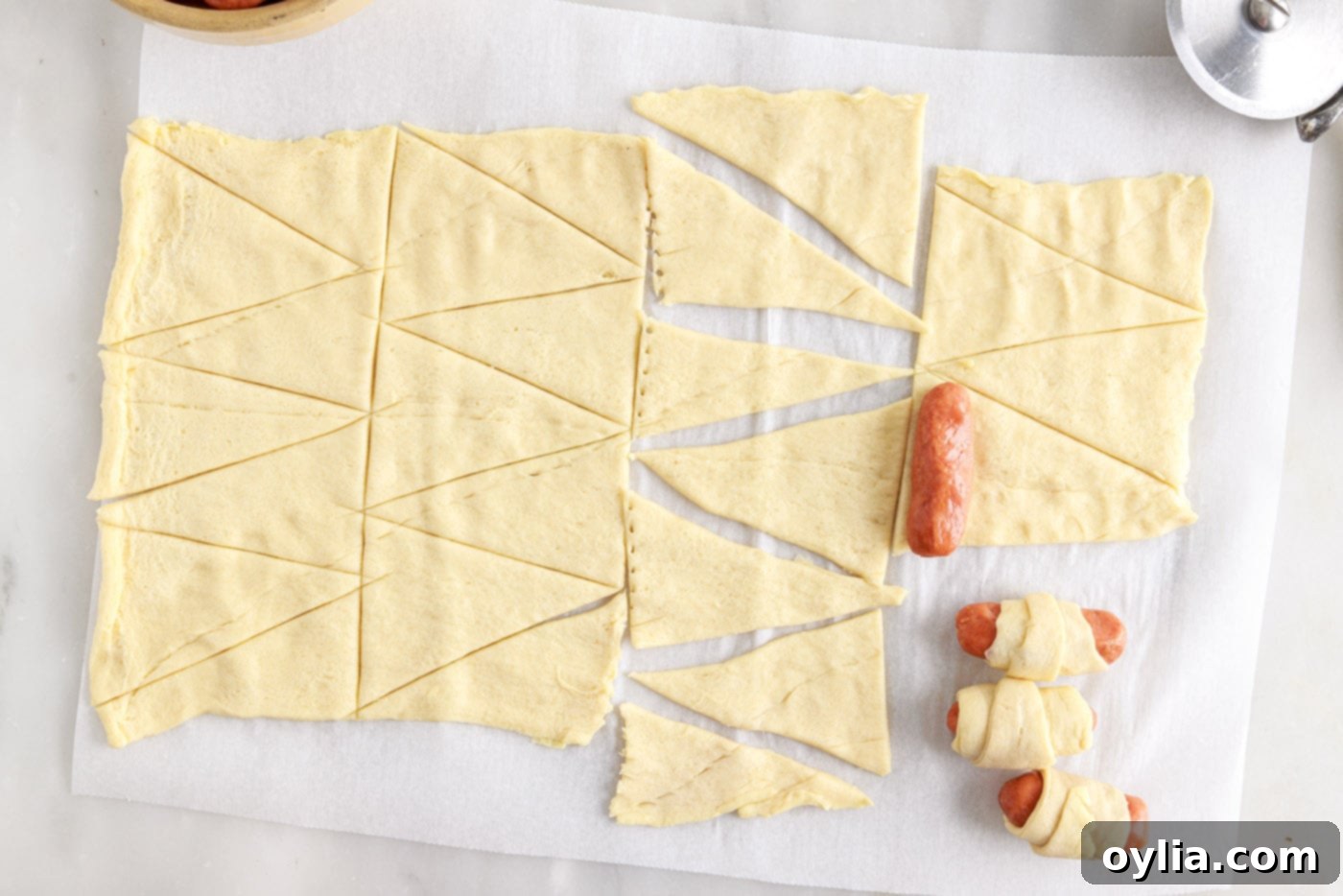 rolling a cocktail sausage into crescent dough, showing the process
