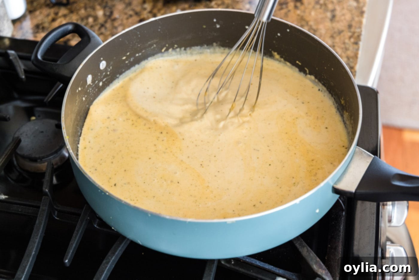Whisking the creamy sauce in a saucepan until smooth and slightly thickened