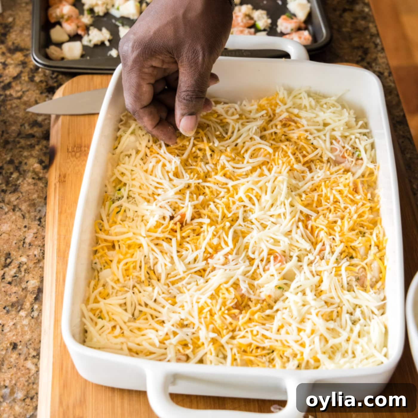 Sprinkling a generous amount of Colby Jack and Mozzarella cheese over the seafood layer