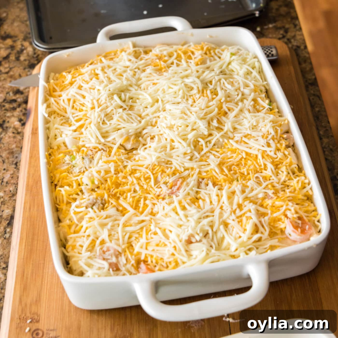 The top layer of seafood lasagna generously covered with shredded cheese, ready for baking