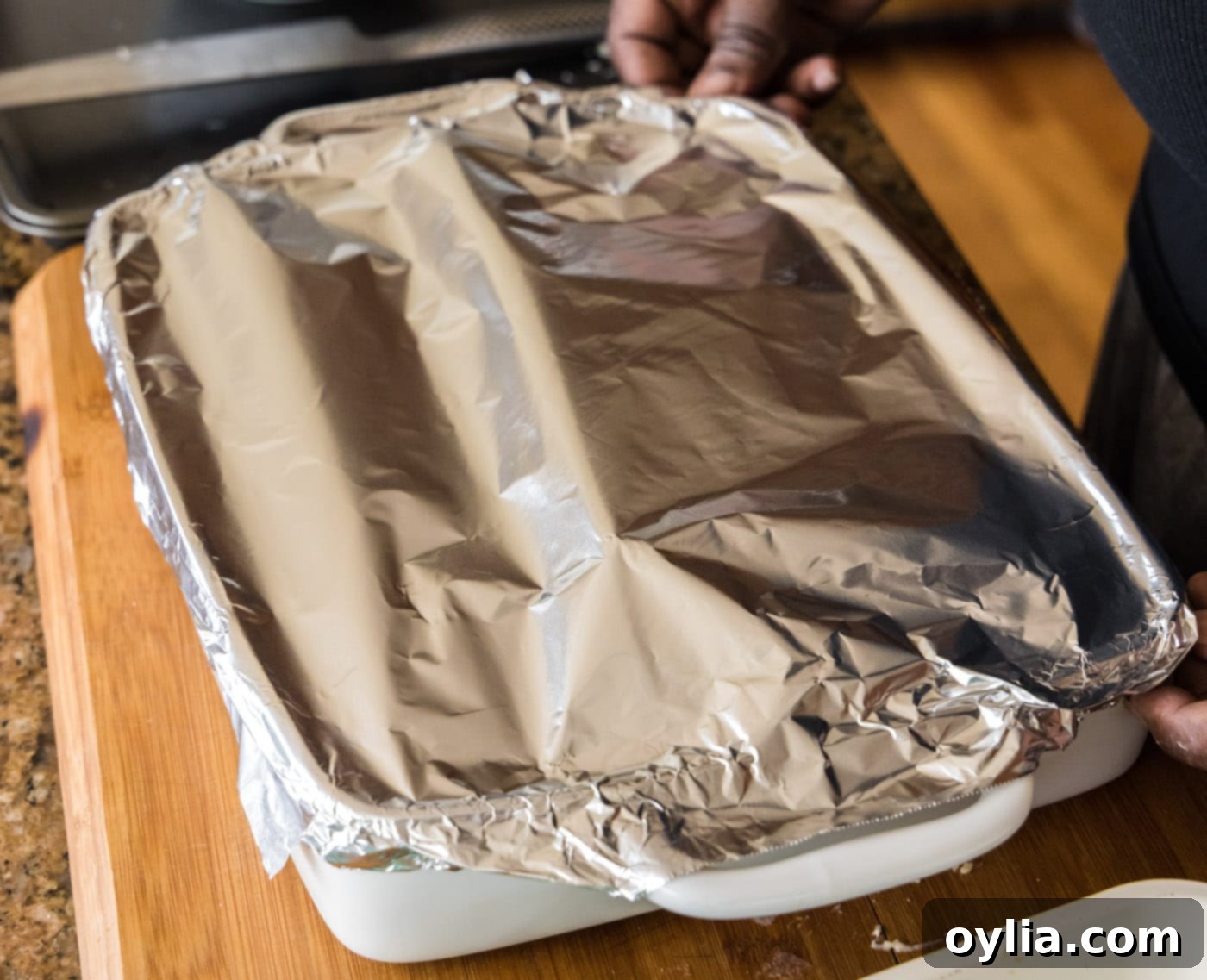 Seafood lasagna in a baking dish, covered tightly with aluminum foil, ready for the oven