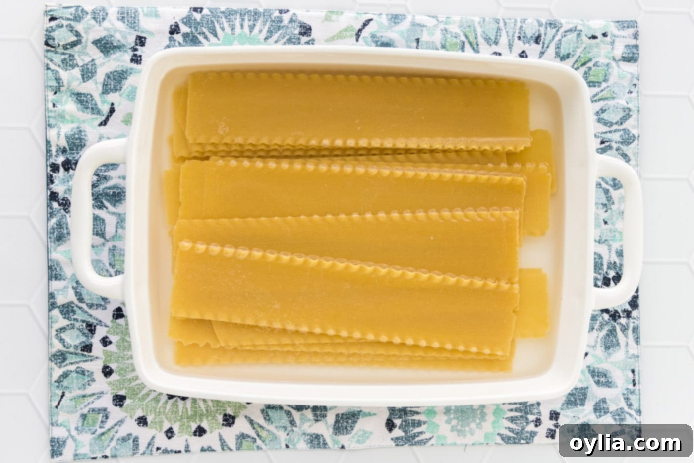 Lasagna noodles soaking in hot water in a baking dish, a no-boil prep method