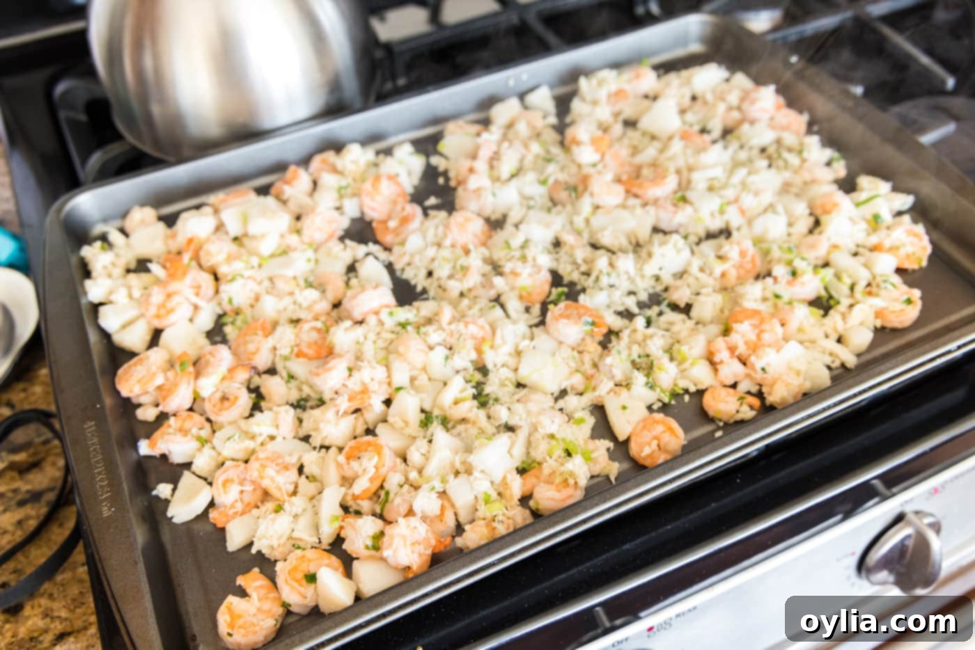 Cooked crab meat, scallops, and shrimp spread on a baking tray to cool