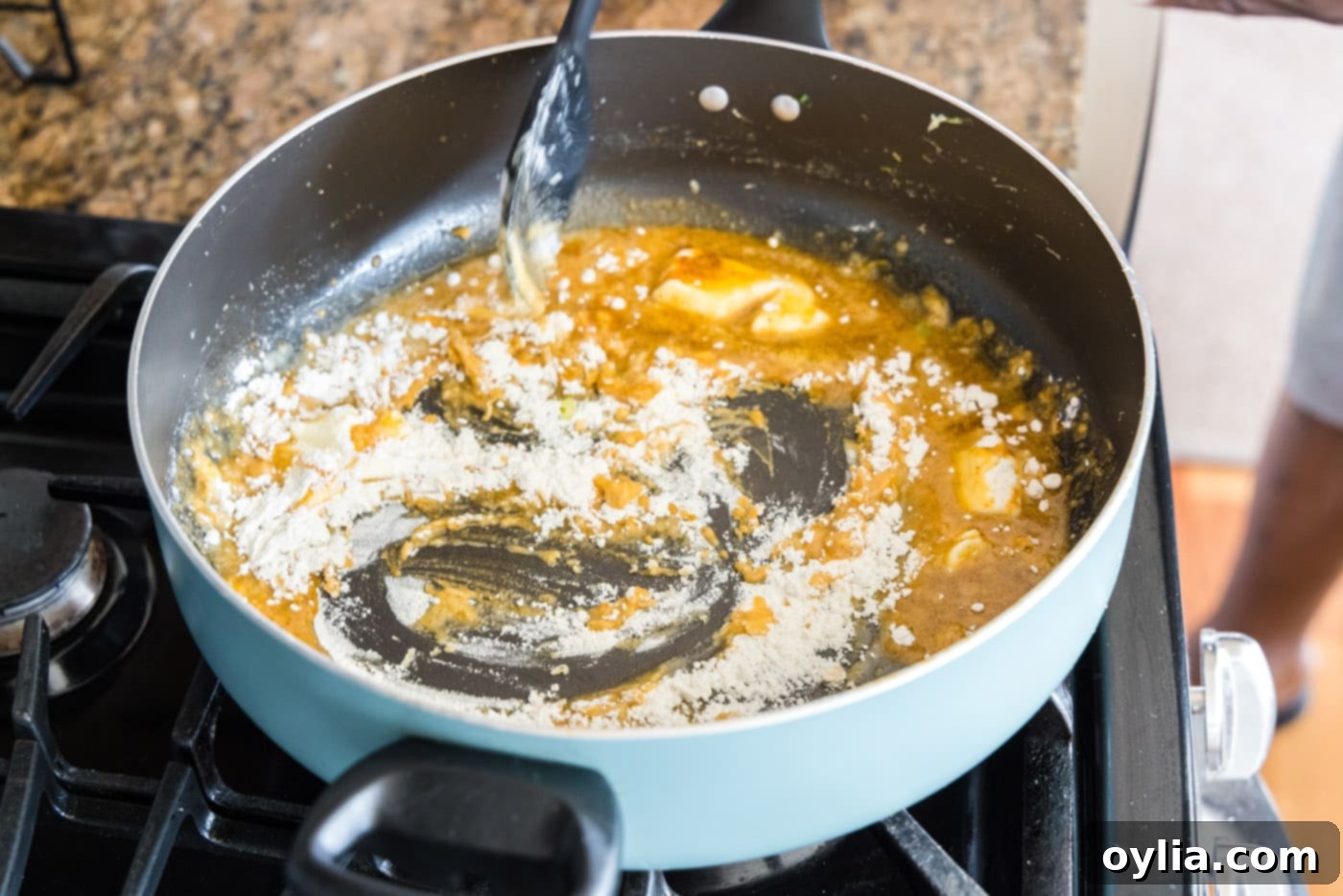 Mixing flour, butter, and seasonings in a skillet to create a roux