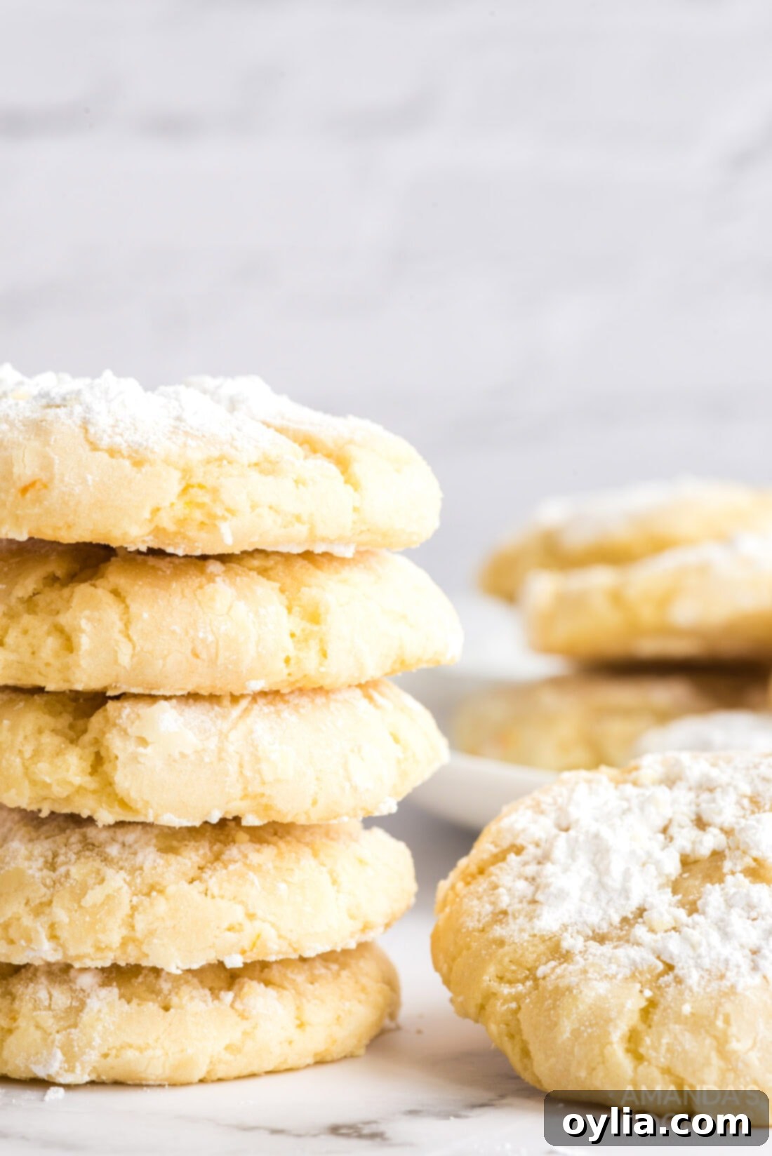 Close-up of a stack of orange crinkle cookies, highlighting their soft texture and unique crackled surface dusted with powdered sugar.