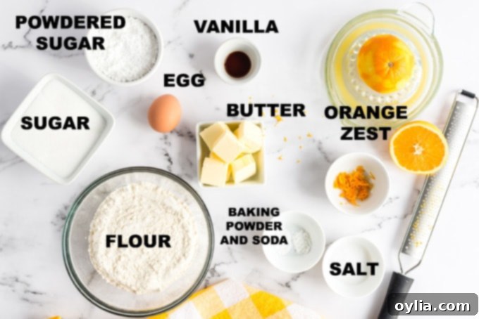 Organized ingredients for orange crinkle cookies laid out on a baking surface, including flour, butter, sugar, egg, orange, and vanilla extract.