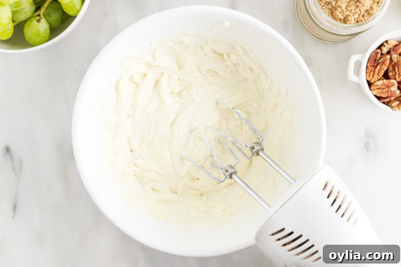 hand mixer beating cream cheese, sour cream, sugar, and vanilla extract