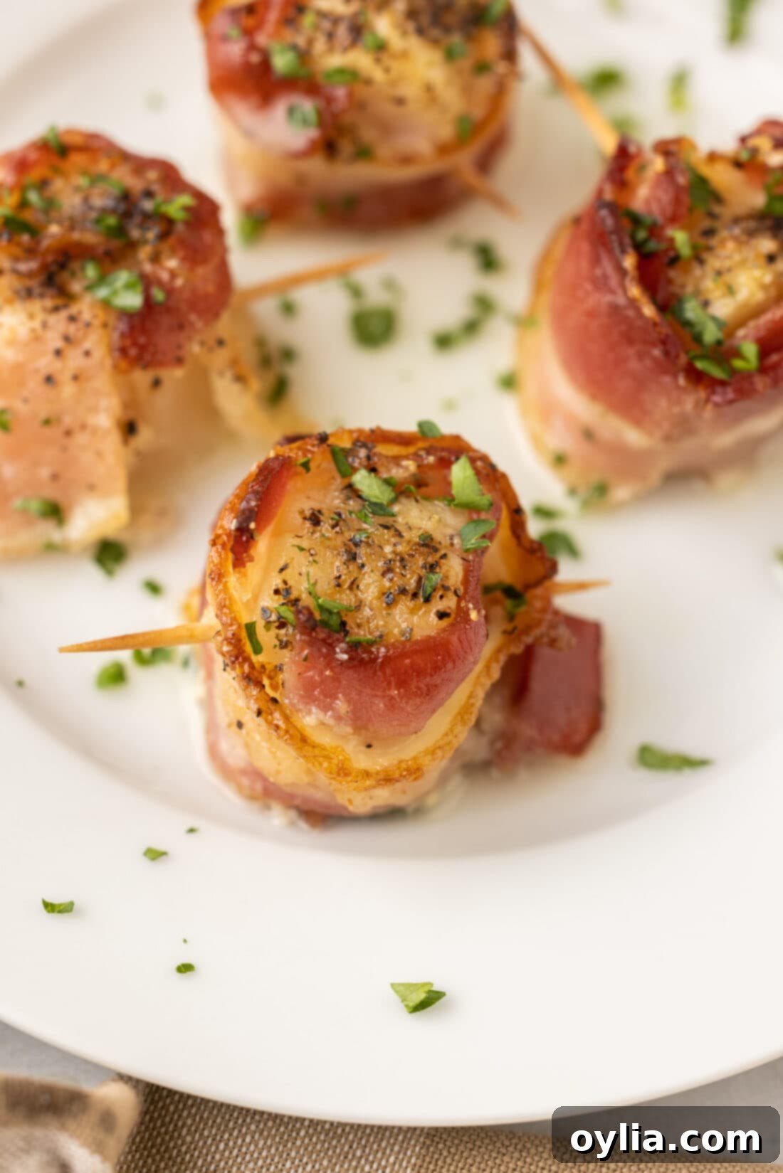 Perfectly cooked bacon wrapped scallops served on a white plate, ready to be enjoyed.