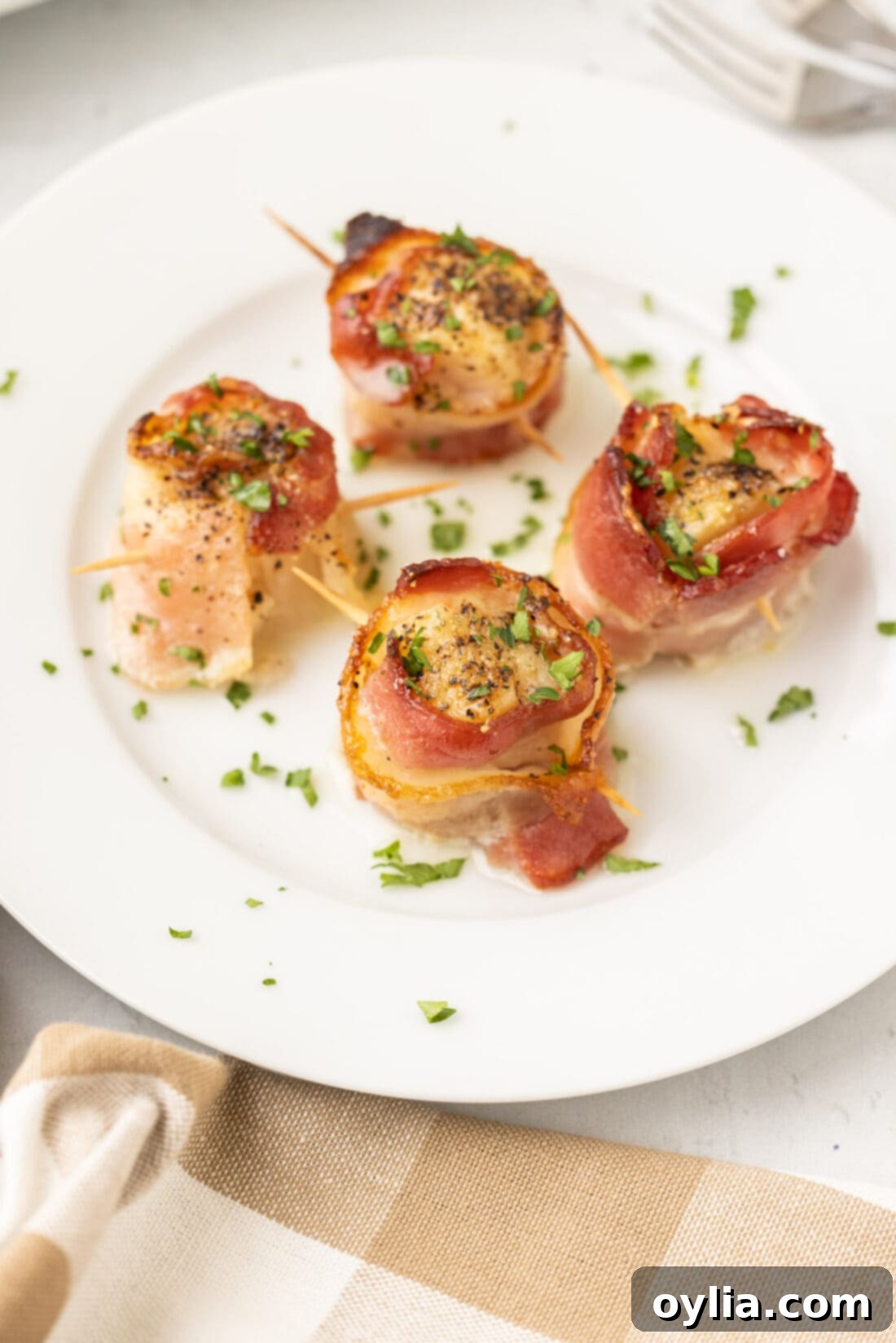 A beautifully arranged platter of golden-brown bacon wrapped scallops, garnished with fresh herbs, ready to be served.