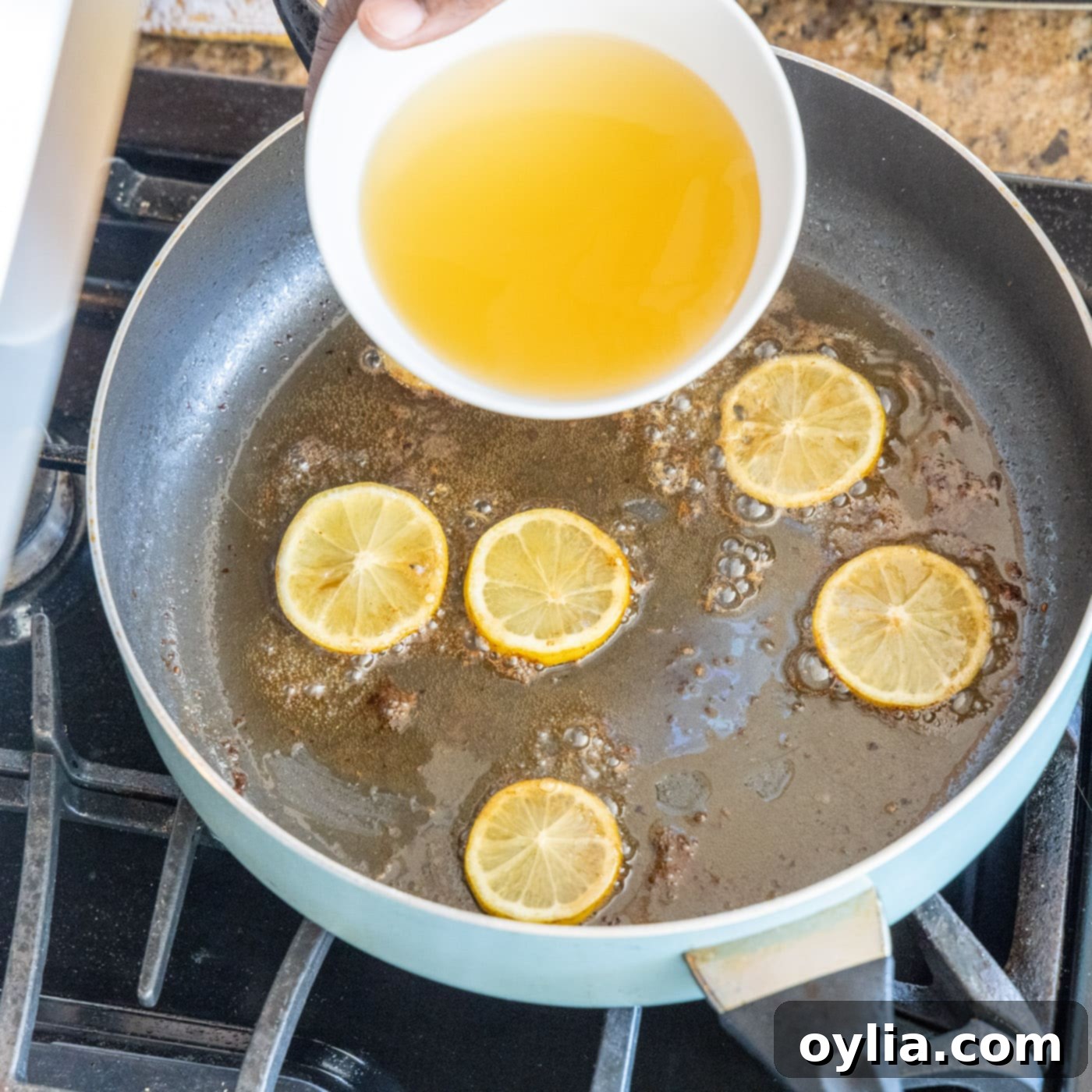 adding chicken stock to lemon and chicken pan juices