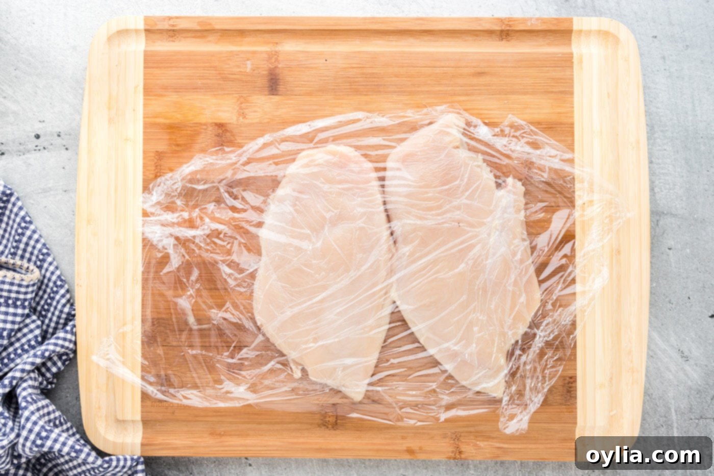 chicken breasts covered with plastic wrap