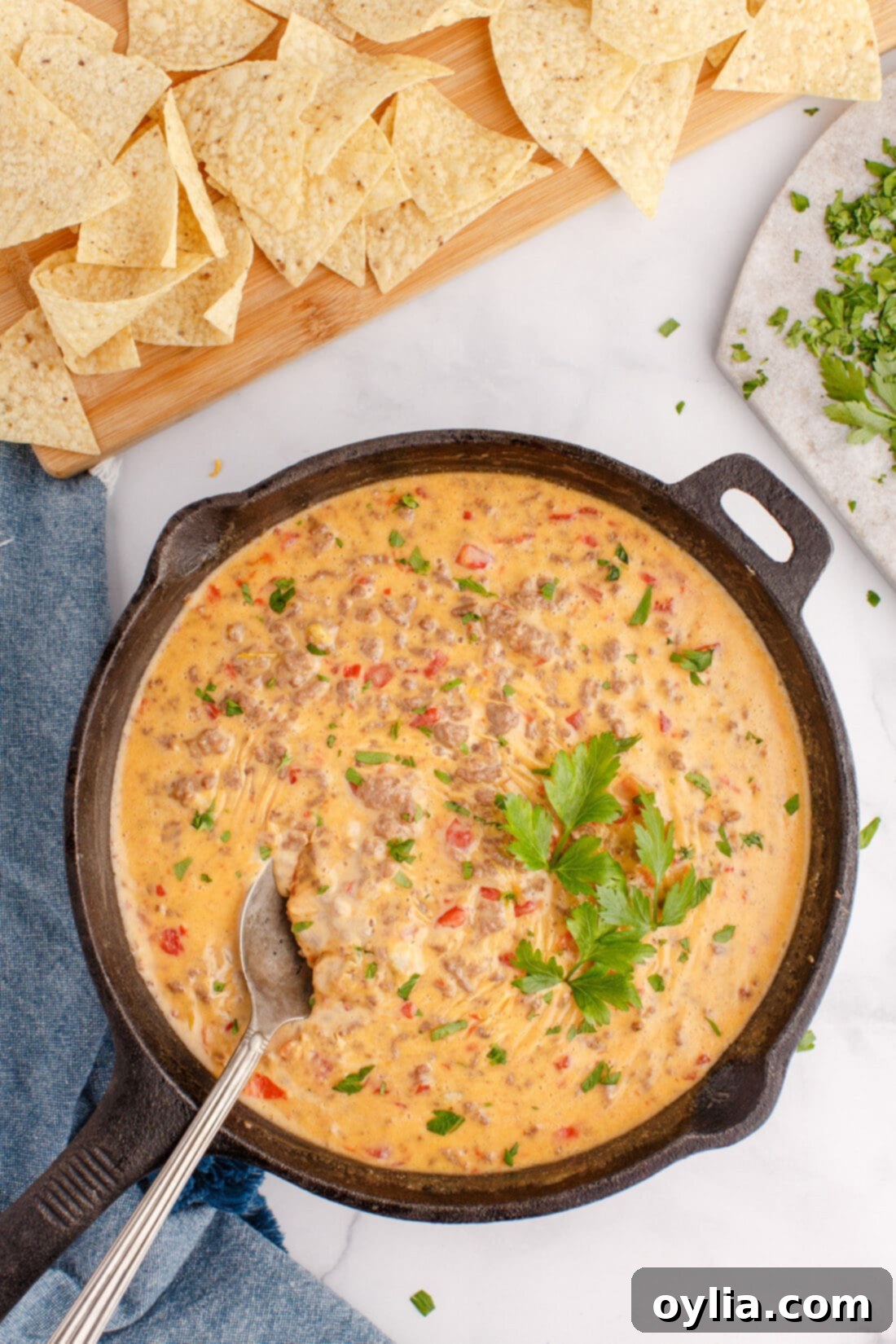 Creamy Chili Cheese Dip 7 Close-up of a pan of Rotel Dip with a serving spoon, garnished with fresh parsley