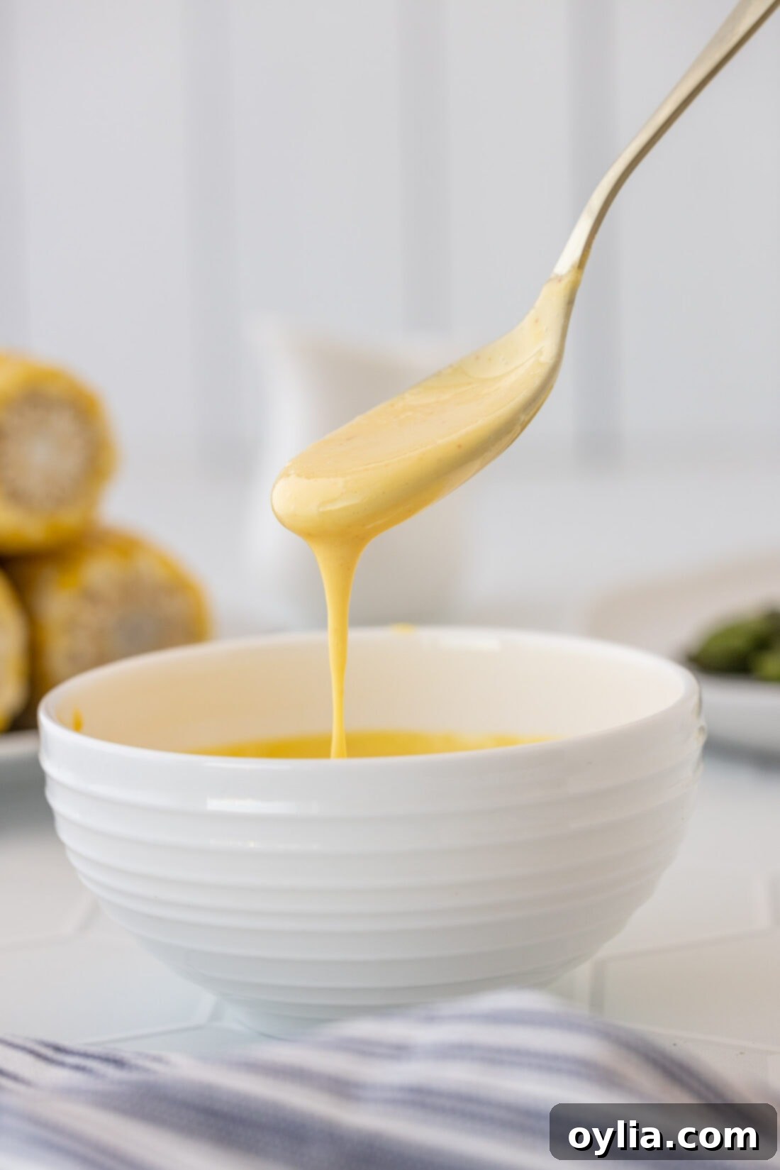 Velvety Hollandaise 2 spoon drizzling Hollandaise Sauce