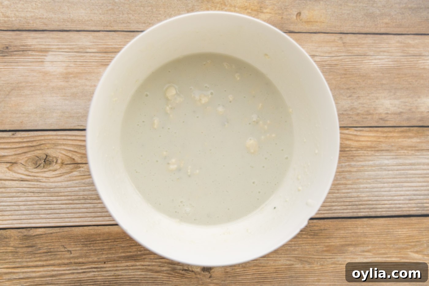Buttermilk and blue cheese crumbles being whisked together in a mixing bowl for dressing.