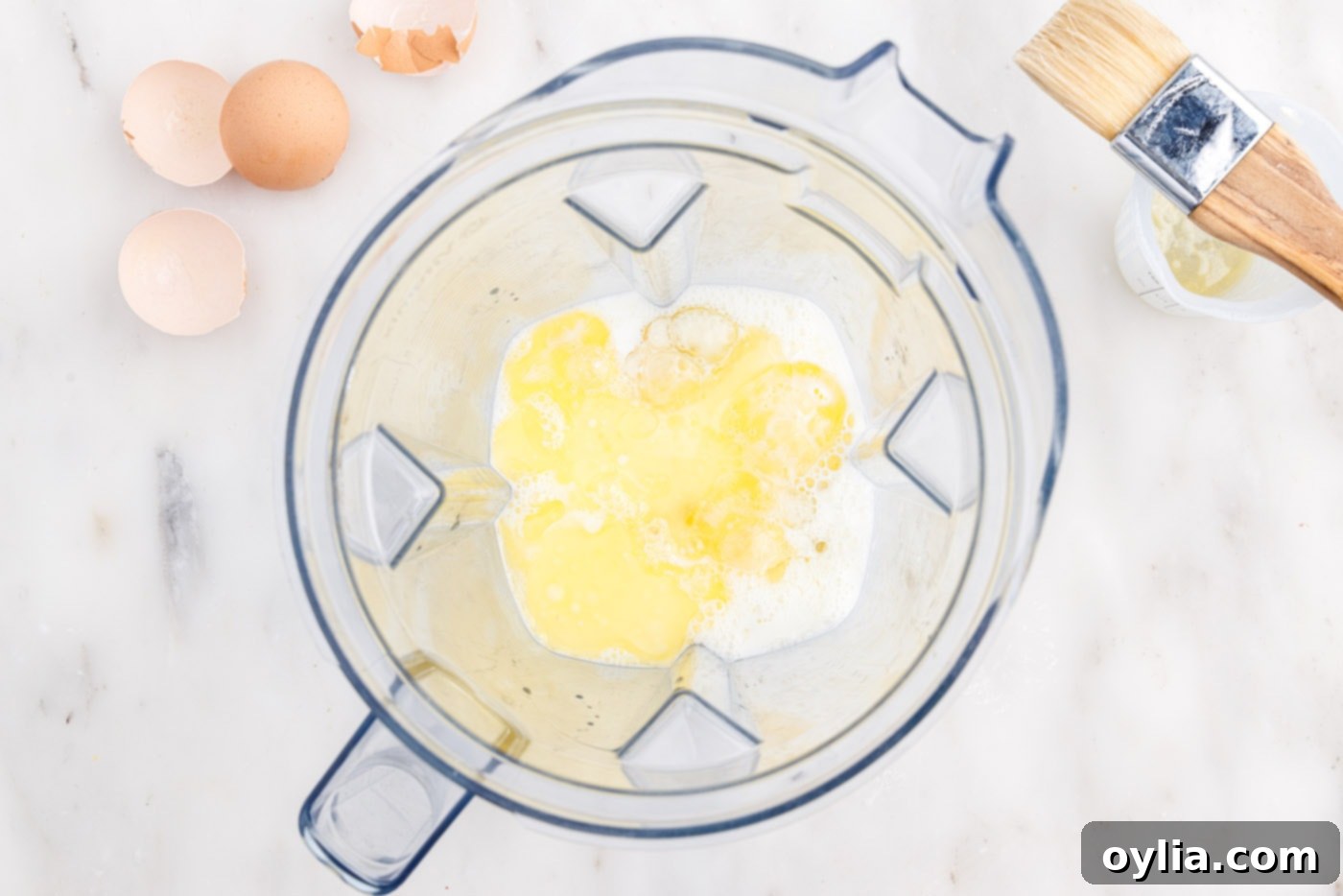 Close-up of melted butter, eggs, and milk being blended in a blender for popover batter.