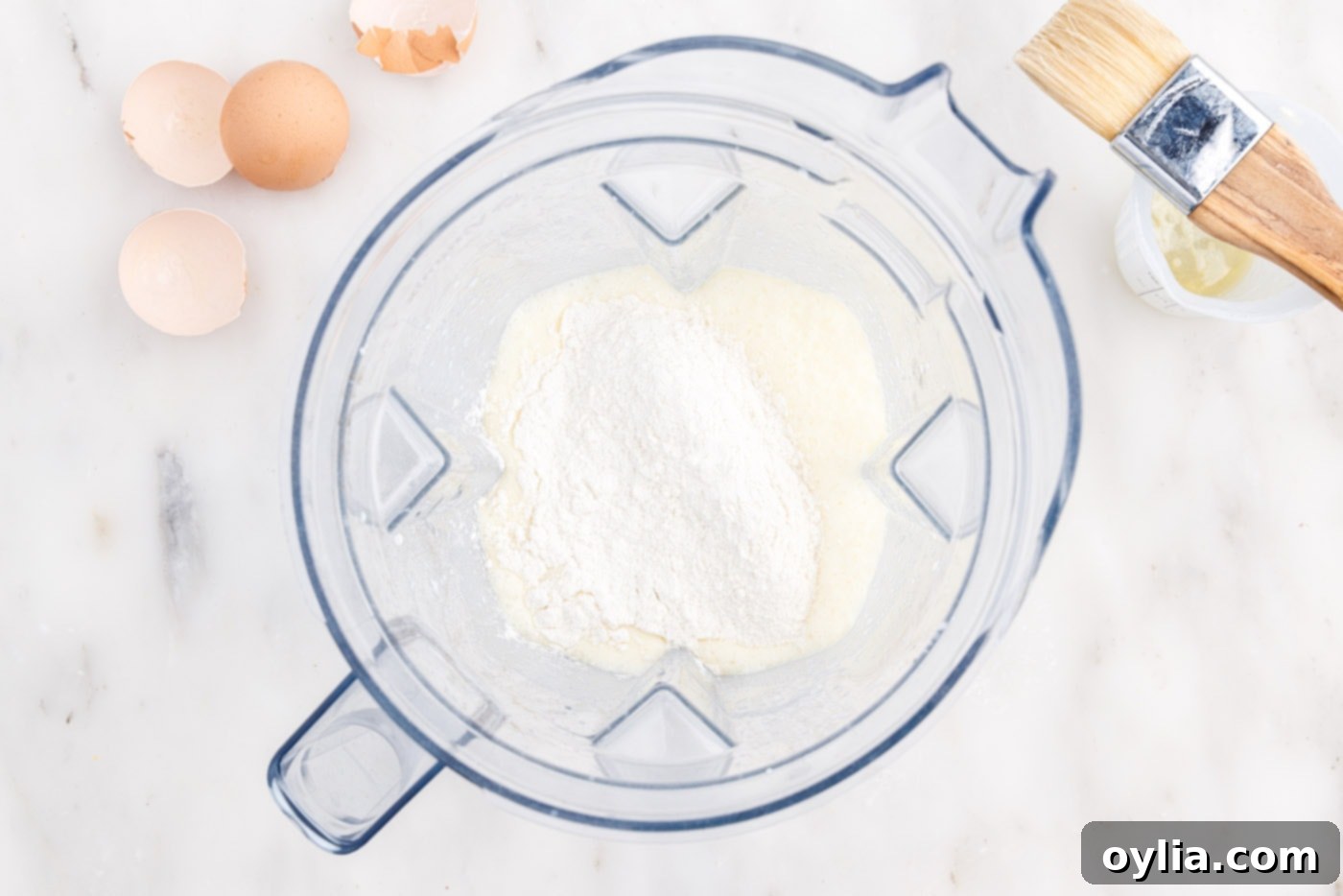 All-purpose flour being added to the wet ingredients in a blender for popover batter.