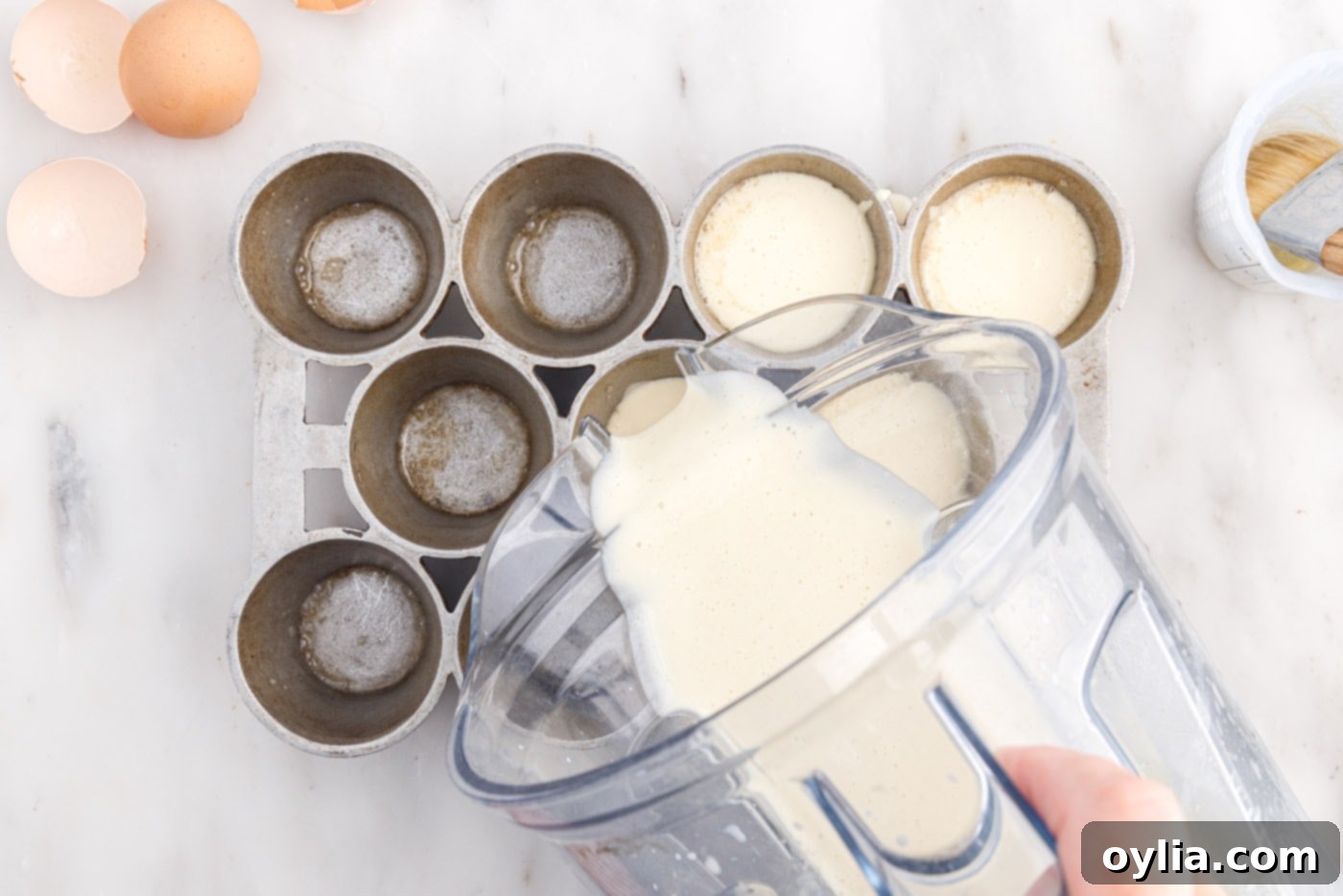 Pouring the smooth popover batter from the blender into the preheated popover tin cups.