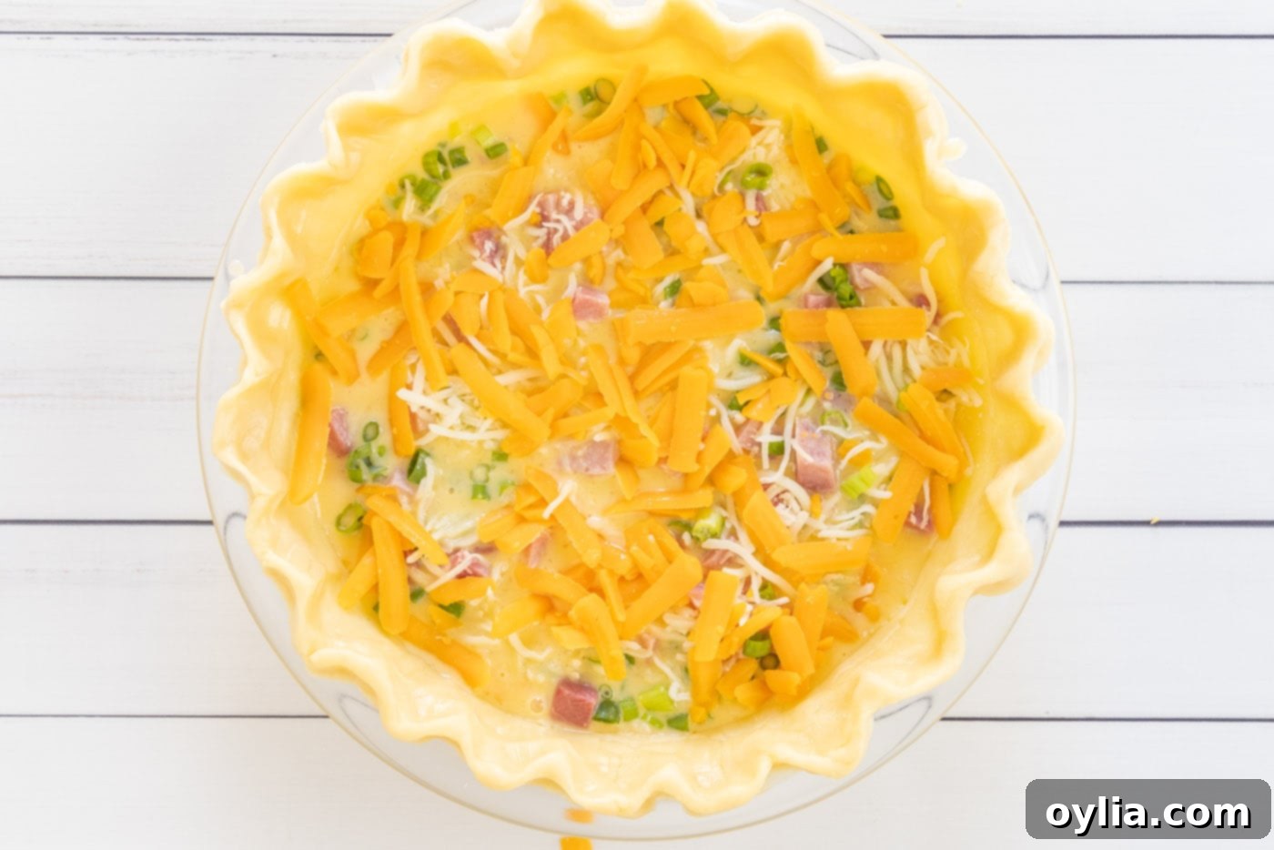 cheddar and mozzarella cheese on top of quiche before baking
