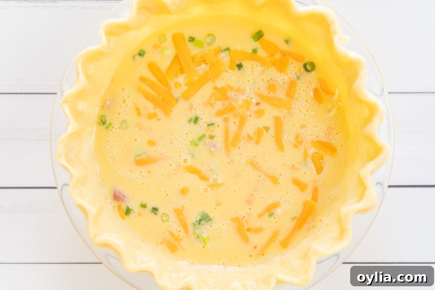 quiche ingredients with egg mixture in pie shell