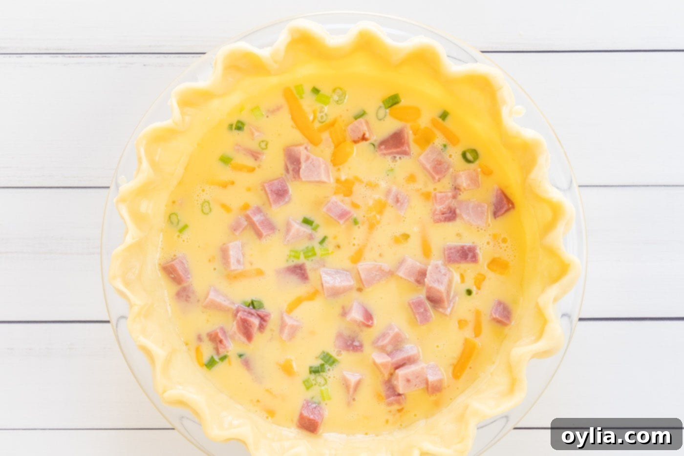 homemade quiche ingredients in a pie shell ready for baking