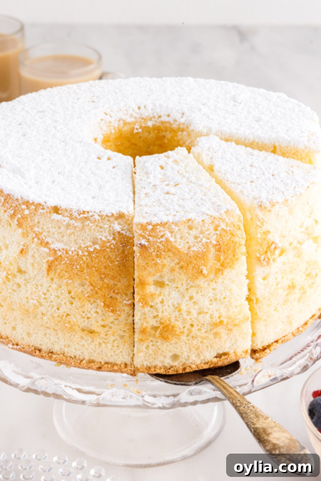 A hand gently removing a slice of Chiffon Cake from a serving platter