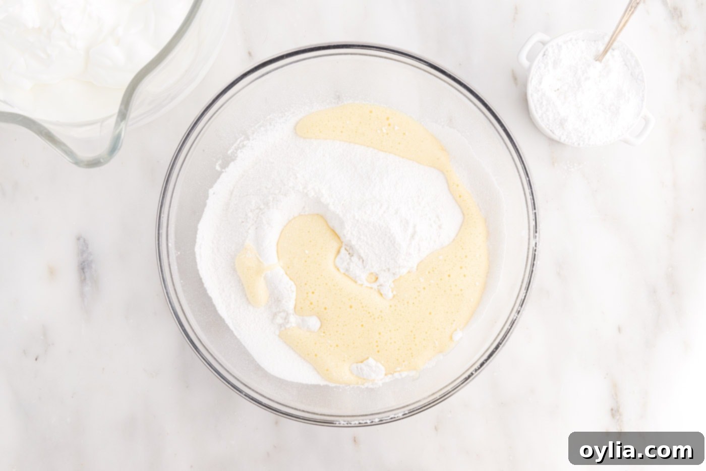 Adding the egg yolk mixture to the dry flour mixture in a bowl