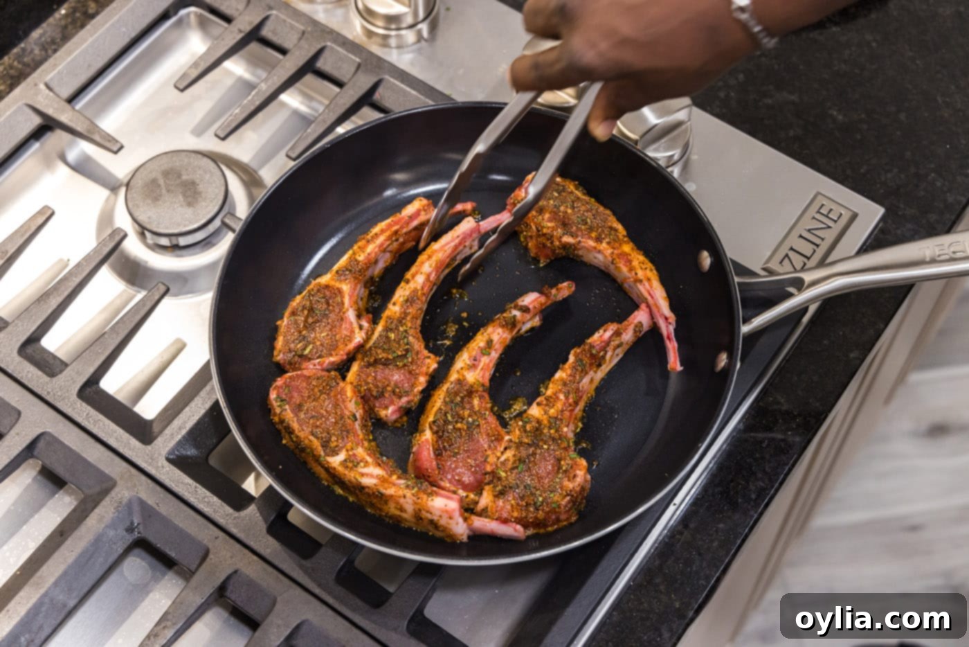 Tongs placing a lamb chop into a hot skillet