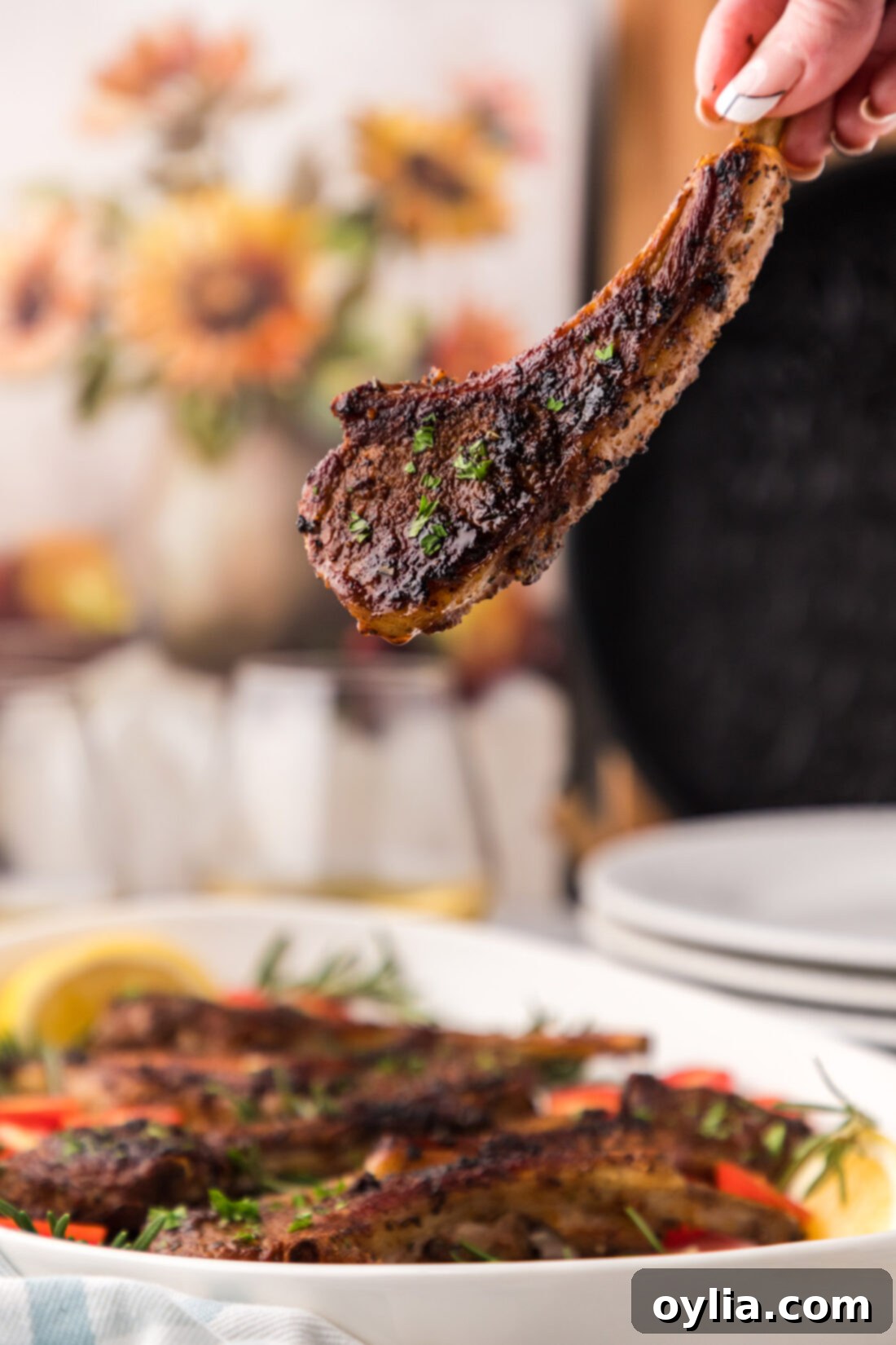 Holding a perfectly cooked Baked Lamb Chop, showing its tender interior