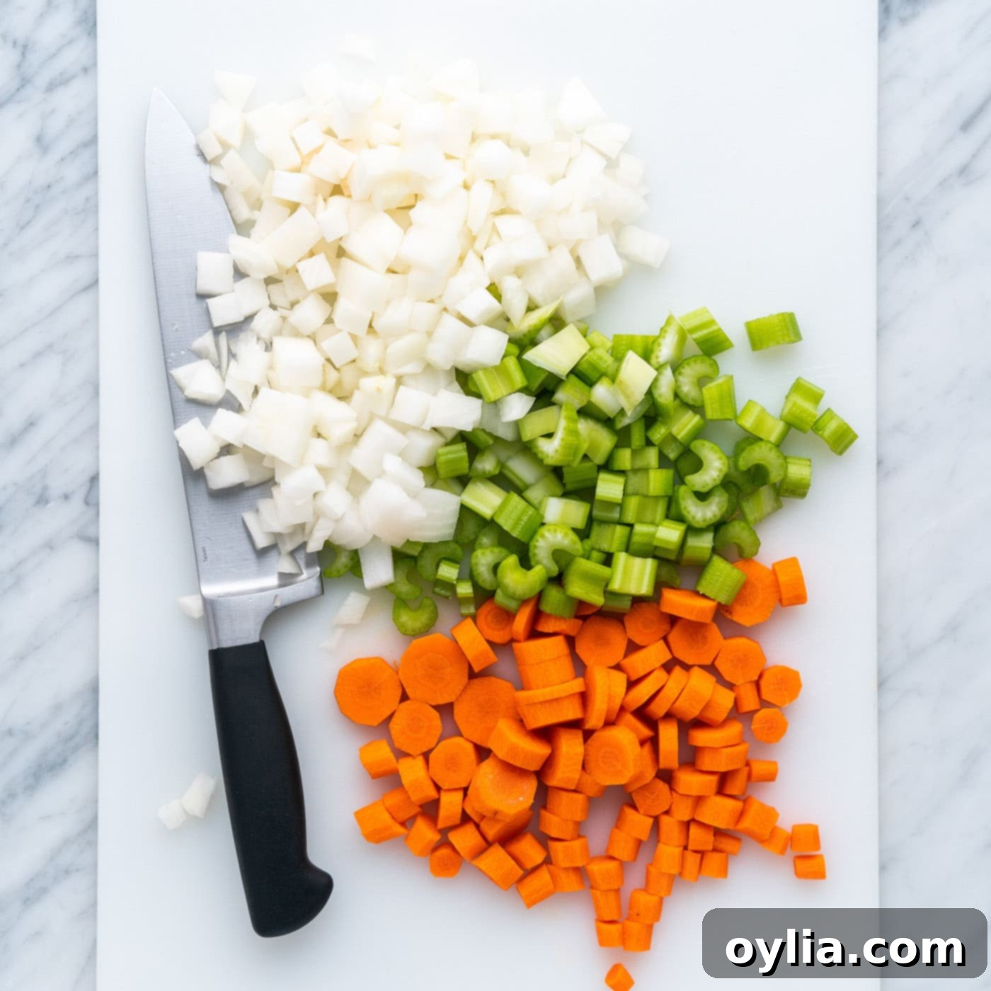diced celery, onion, and carrots on a cutting board