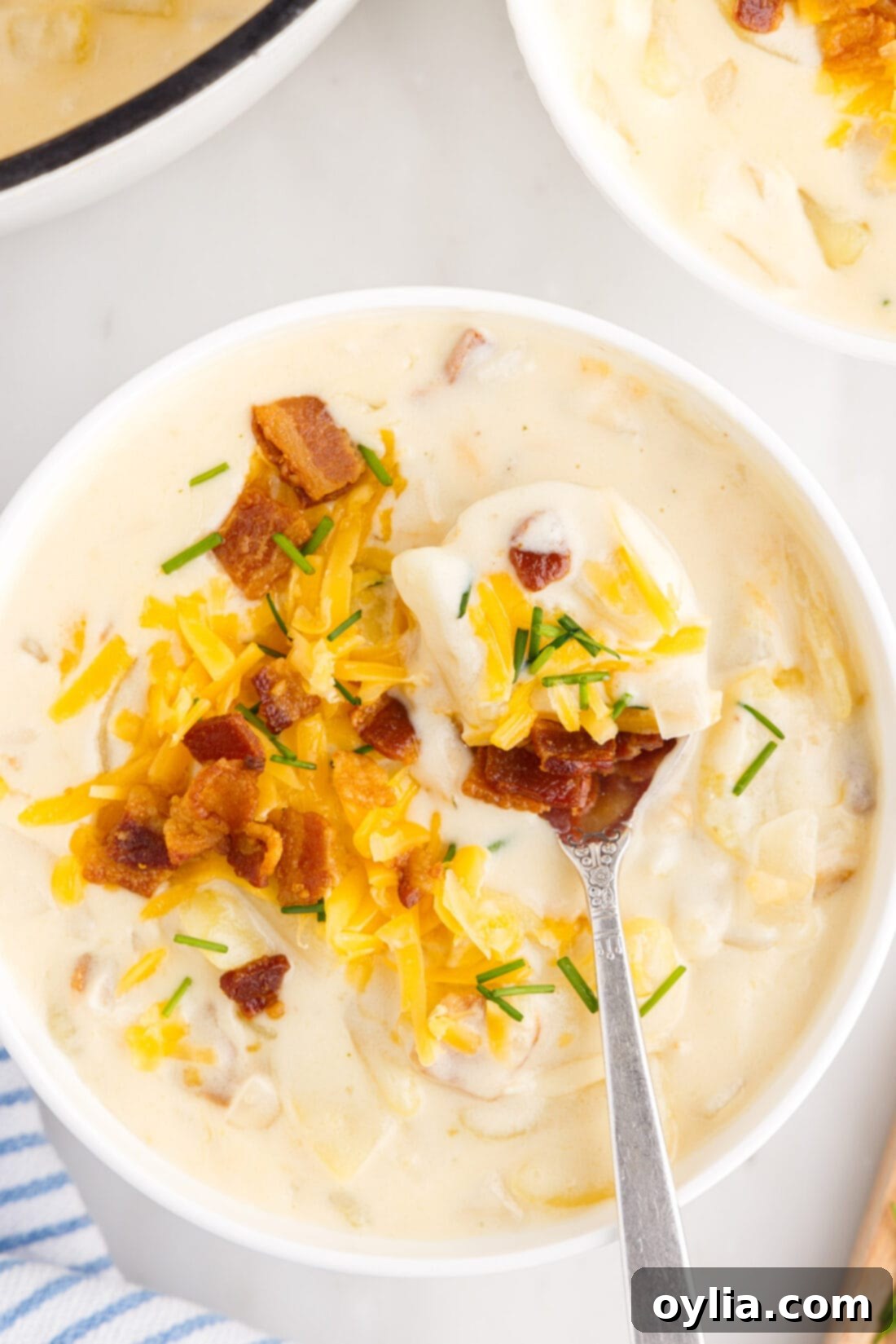 Spoonful of Baked Potato Soup over a bowl of Baked Potato Soup