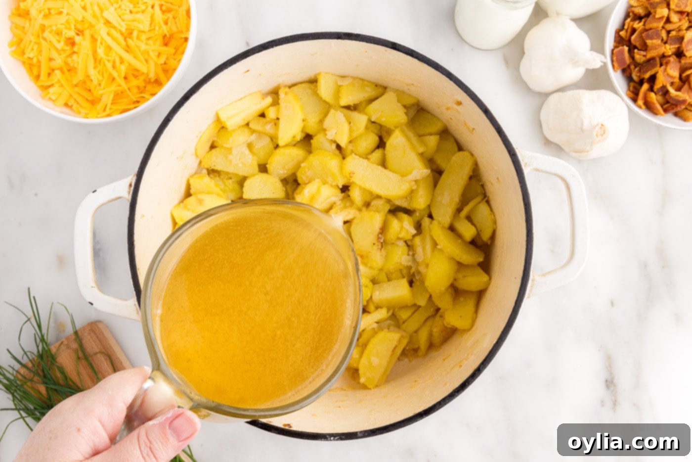 adding chicken broth to potato soup