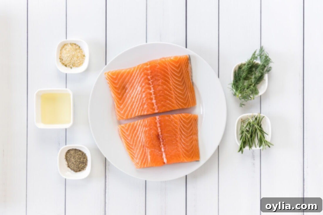 Fresh salmon fillets, olive oil, garlic salt, black pepper, rosemary, and dill sprigs laid out as ingredients for sous vide salmon