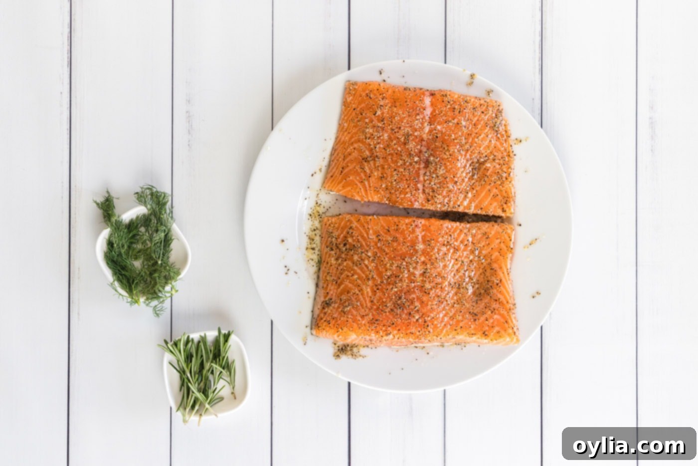 Fresh salmon filet being rubbed with olive oil and a savory seasoning mixture