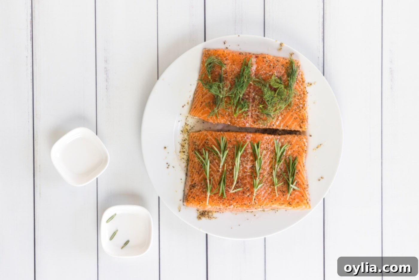 Fresh rosemary and dill sprigs placed on top of seasoned salmon filets, ready for vacuum sealing