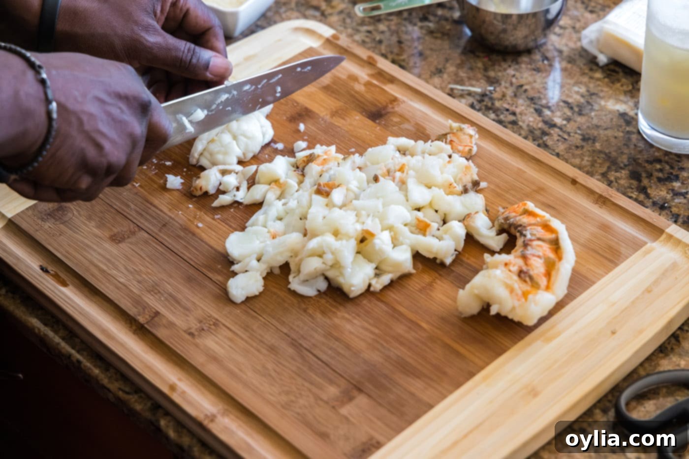 Chopped cooked lobster meat on a cutting board, ready to be added to the sauce.