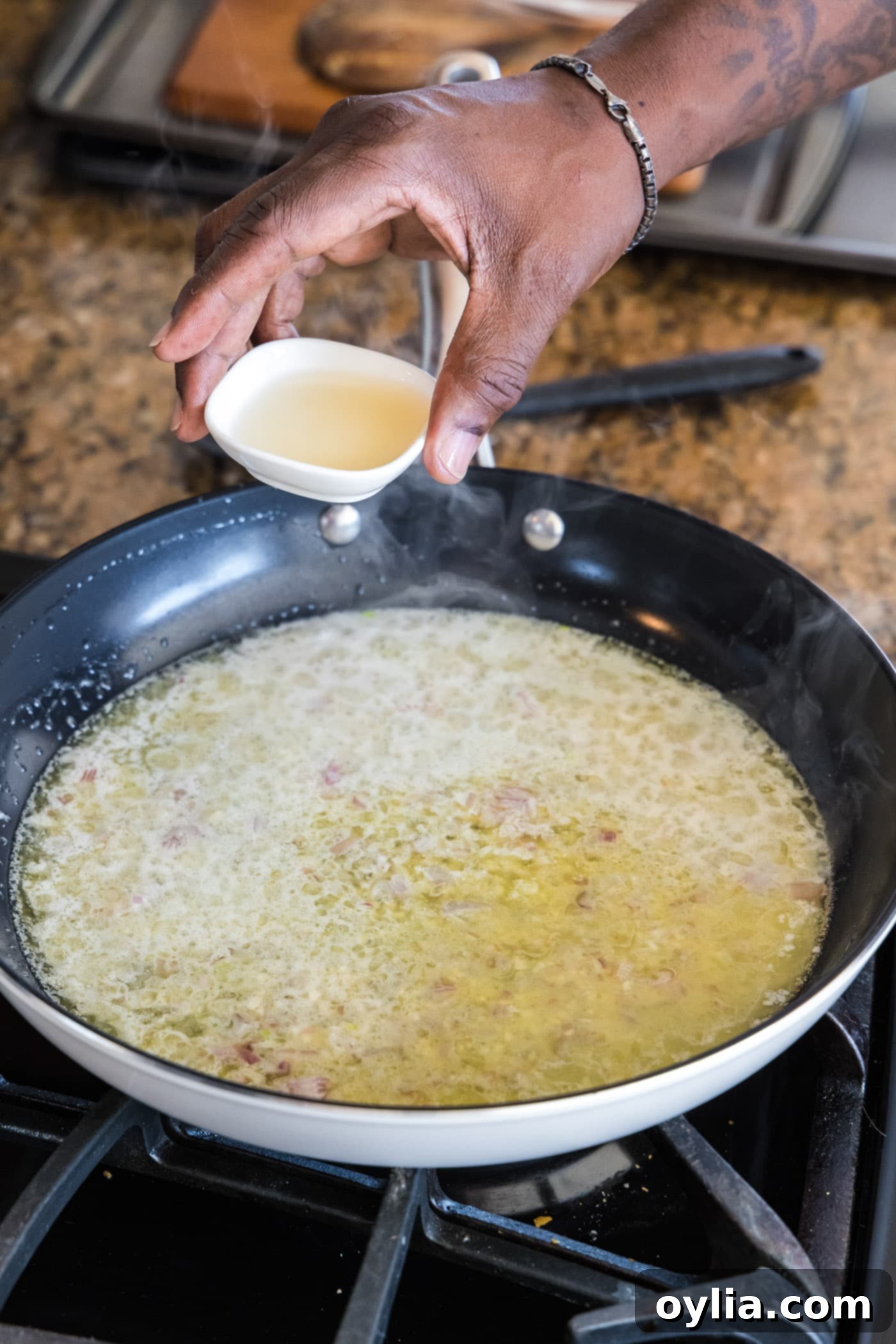 Adding white wine to the shallot, garlic, and butter mixture in a skillet.