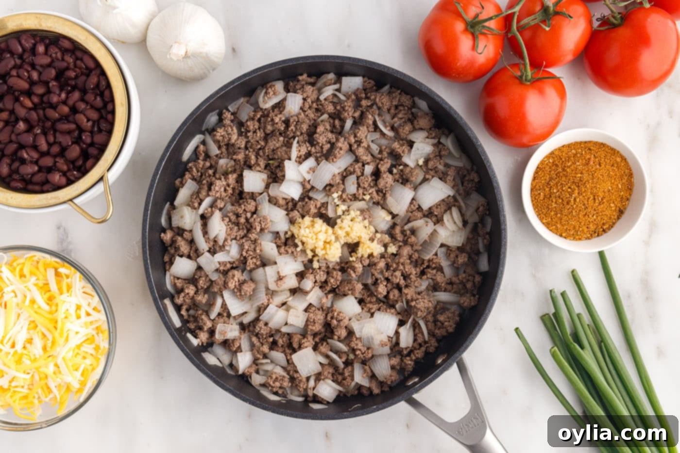 adding garlic to ground beef and onion in a skillet