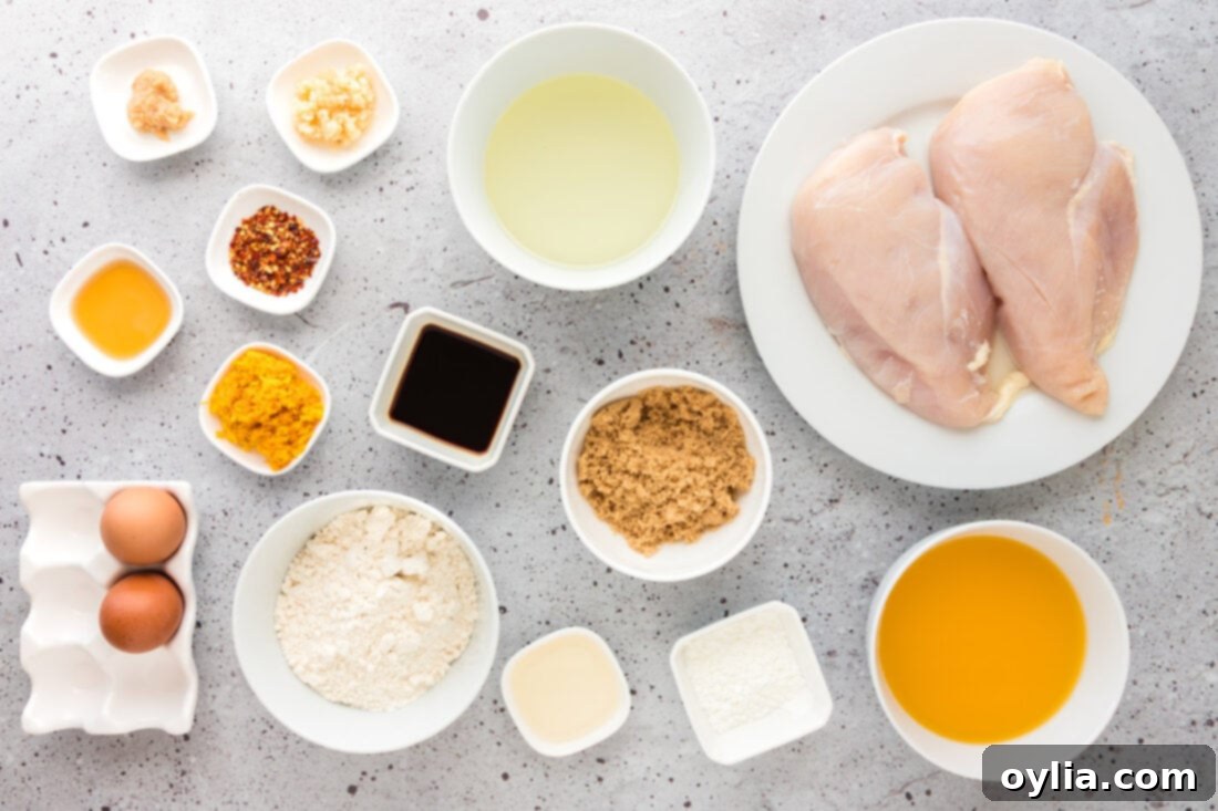 A collection of fresh ingredients laid out for making Orange Chicken, including oranges, chicken, and sauce components.