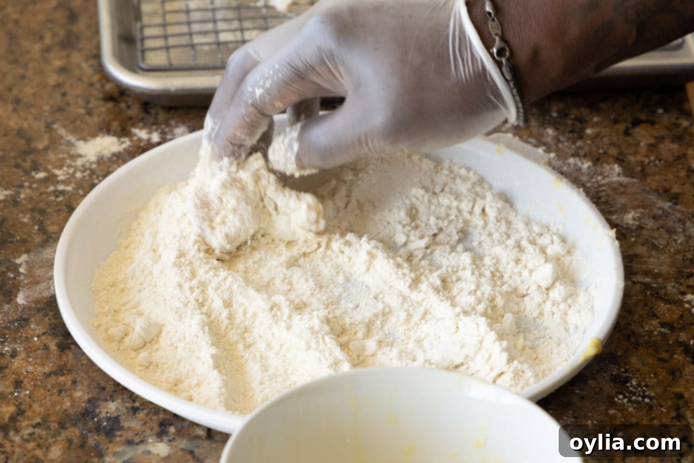 Chicken piece being dredged for the second time in flour