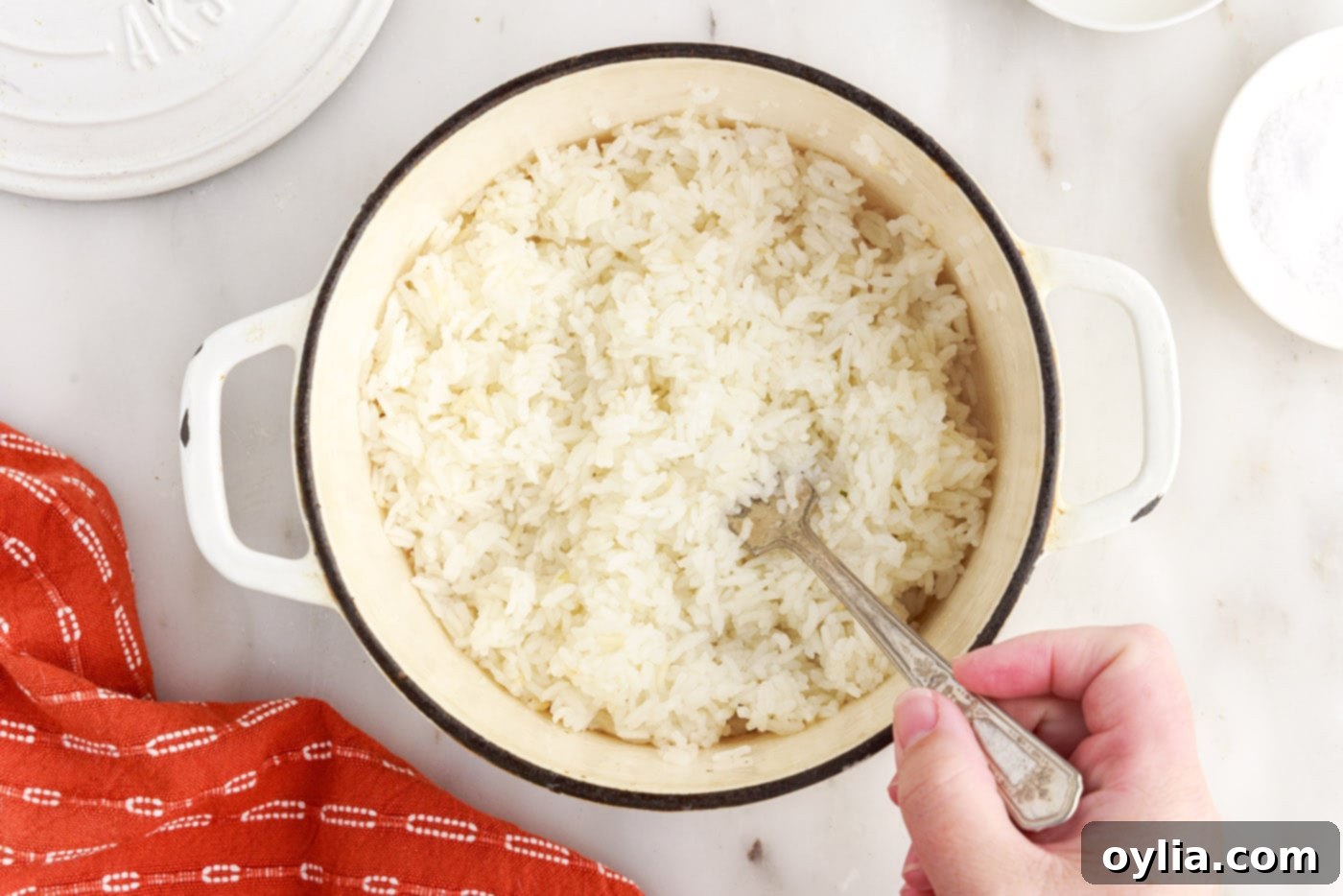 fluffing white rice with a fork in a saucepan