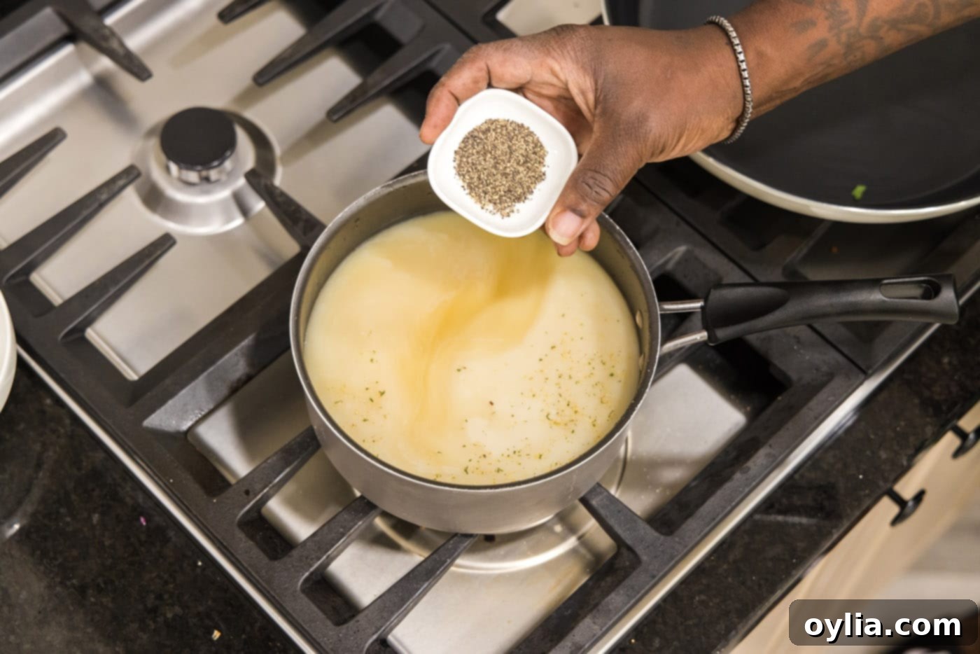 Chicken broth, milk, garlic salt, and pepper simmering in a saucepan for grits base.
