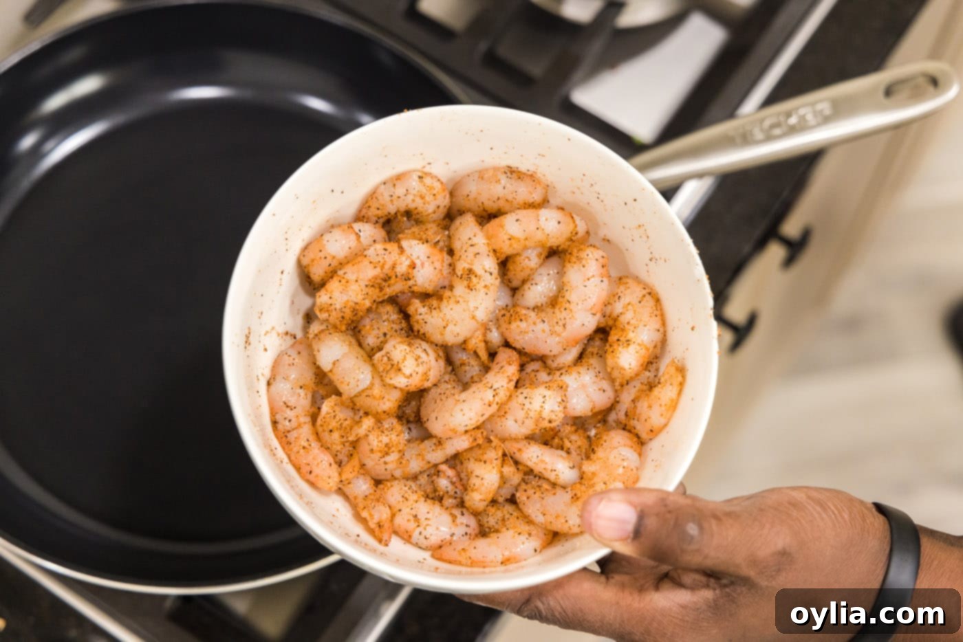 Raw shrimp seasoned with Cajun spices in a bowl, ready for cooking.