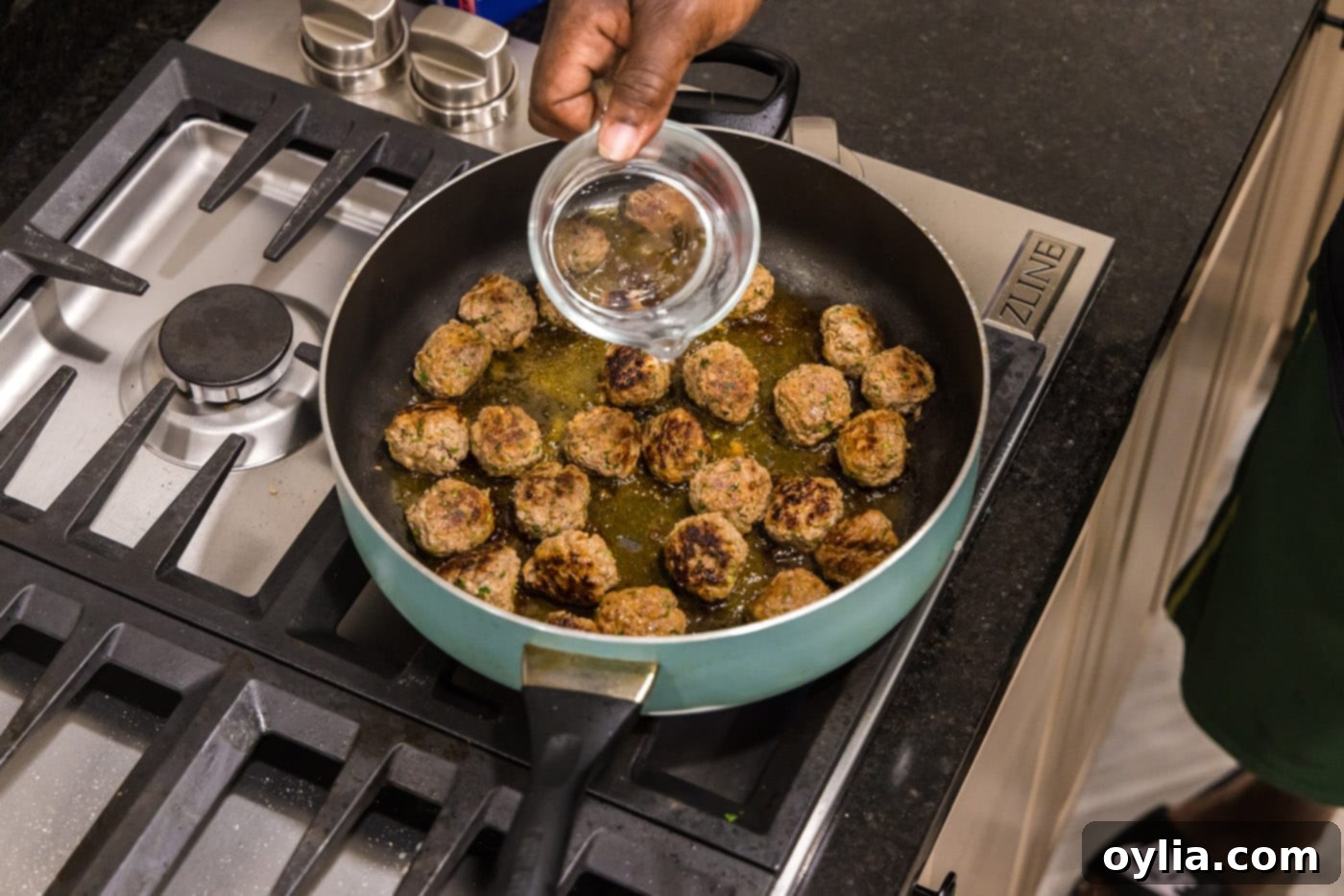 adding water to meatballs in a skillet