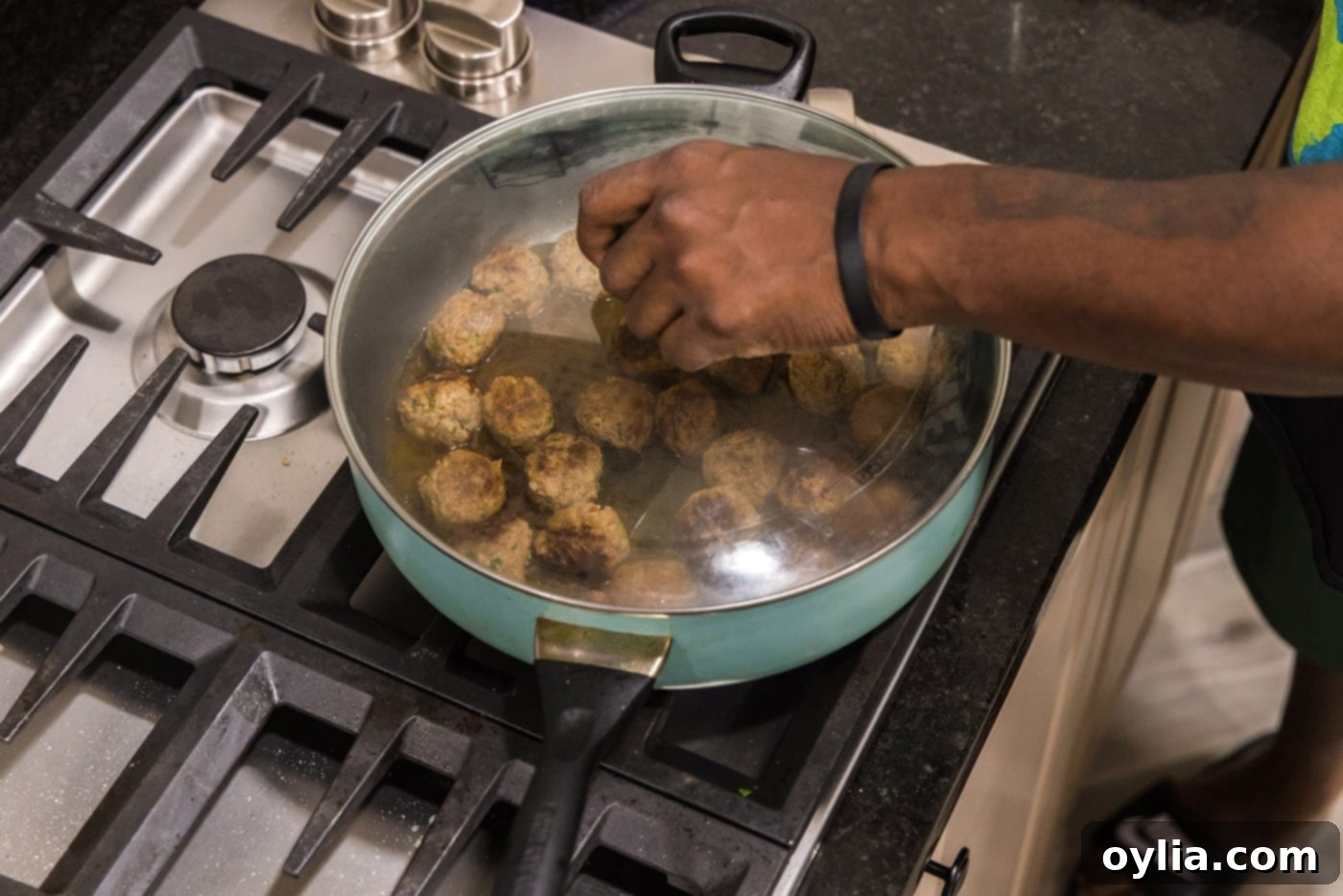 adding a lid to skillet with meatballs