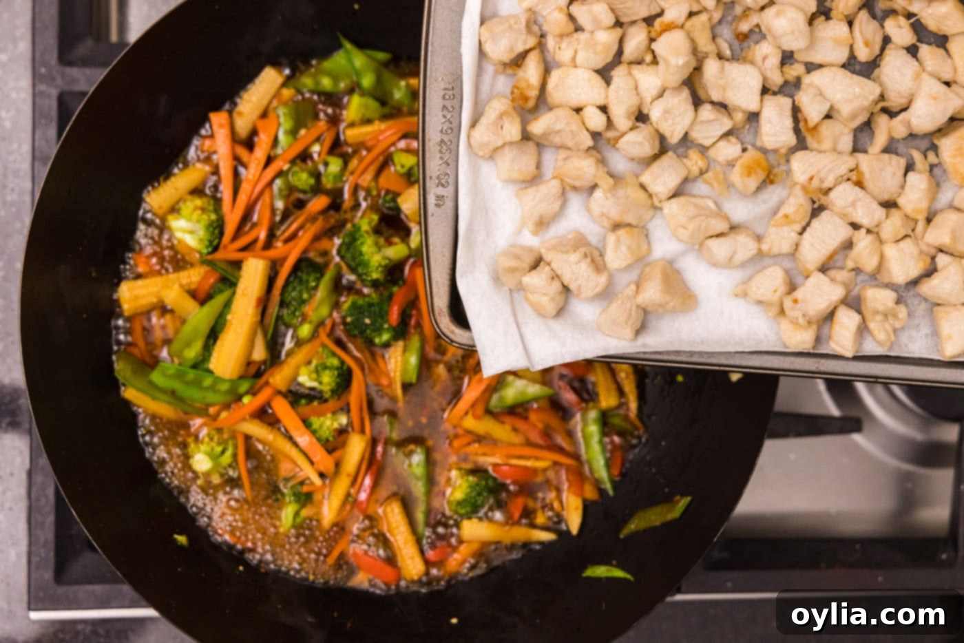 adding chicken back to wok with vegetables and sauce