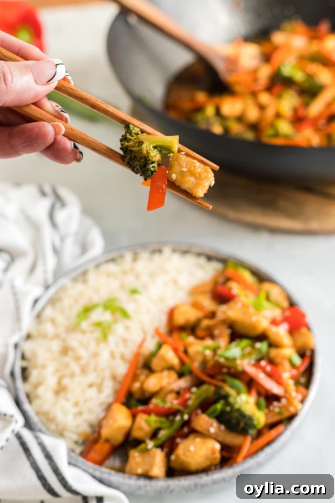 Pieces of Hunan Chicken held in chopsticks 