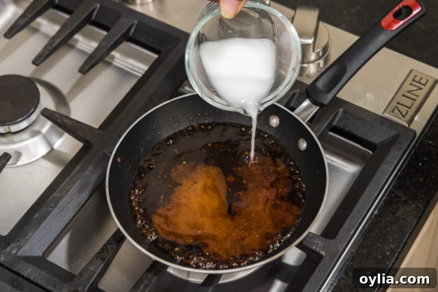 pouring cornstarch slurry into sauce in a skillet