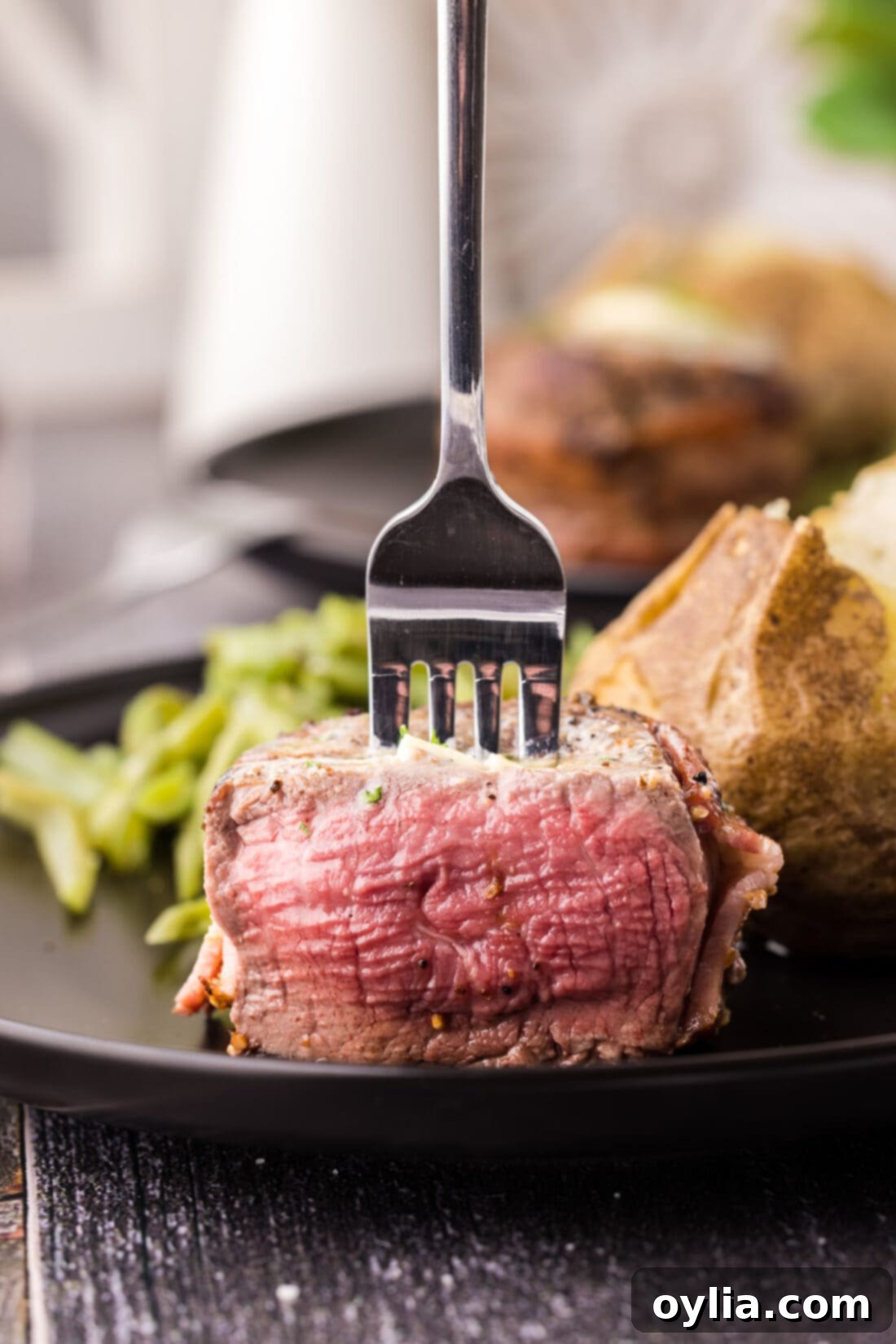 Close up of a fork in a Bacon Wrapped Filet Mignon, showcasing its perfect sear and juicy interior.