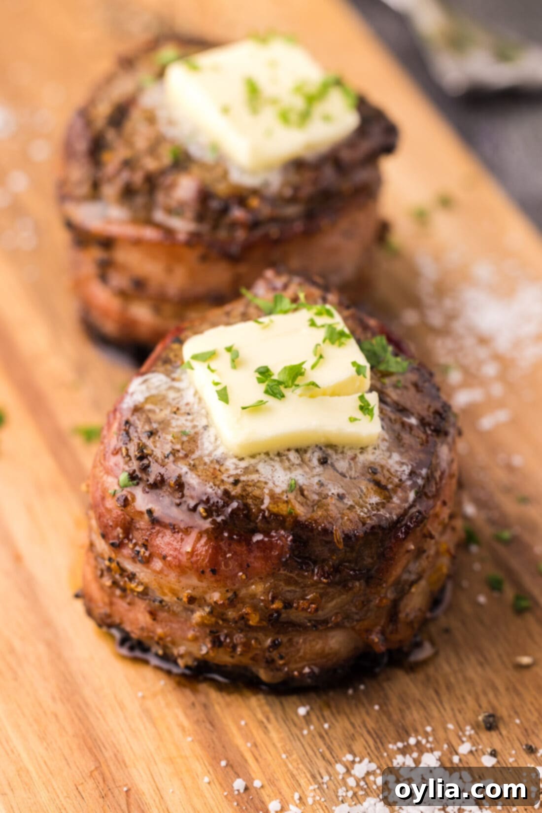Two perfectly cooked Bacon Wrapped Filet Mignons arranged artfully on a platter, ready to be served.