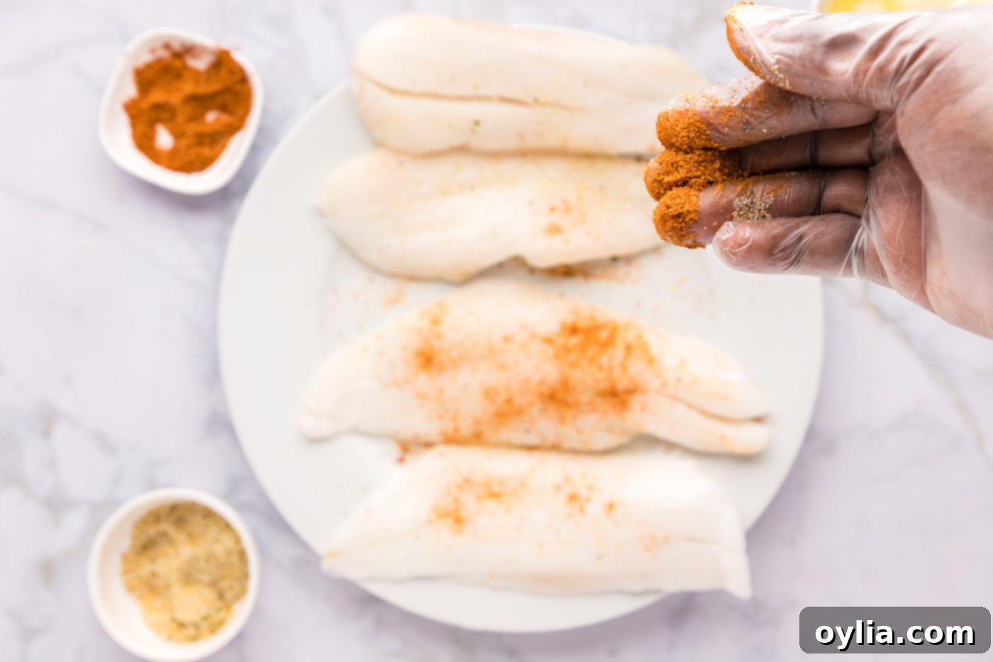 Hand rubbing seasonings onto orange roughy filets